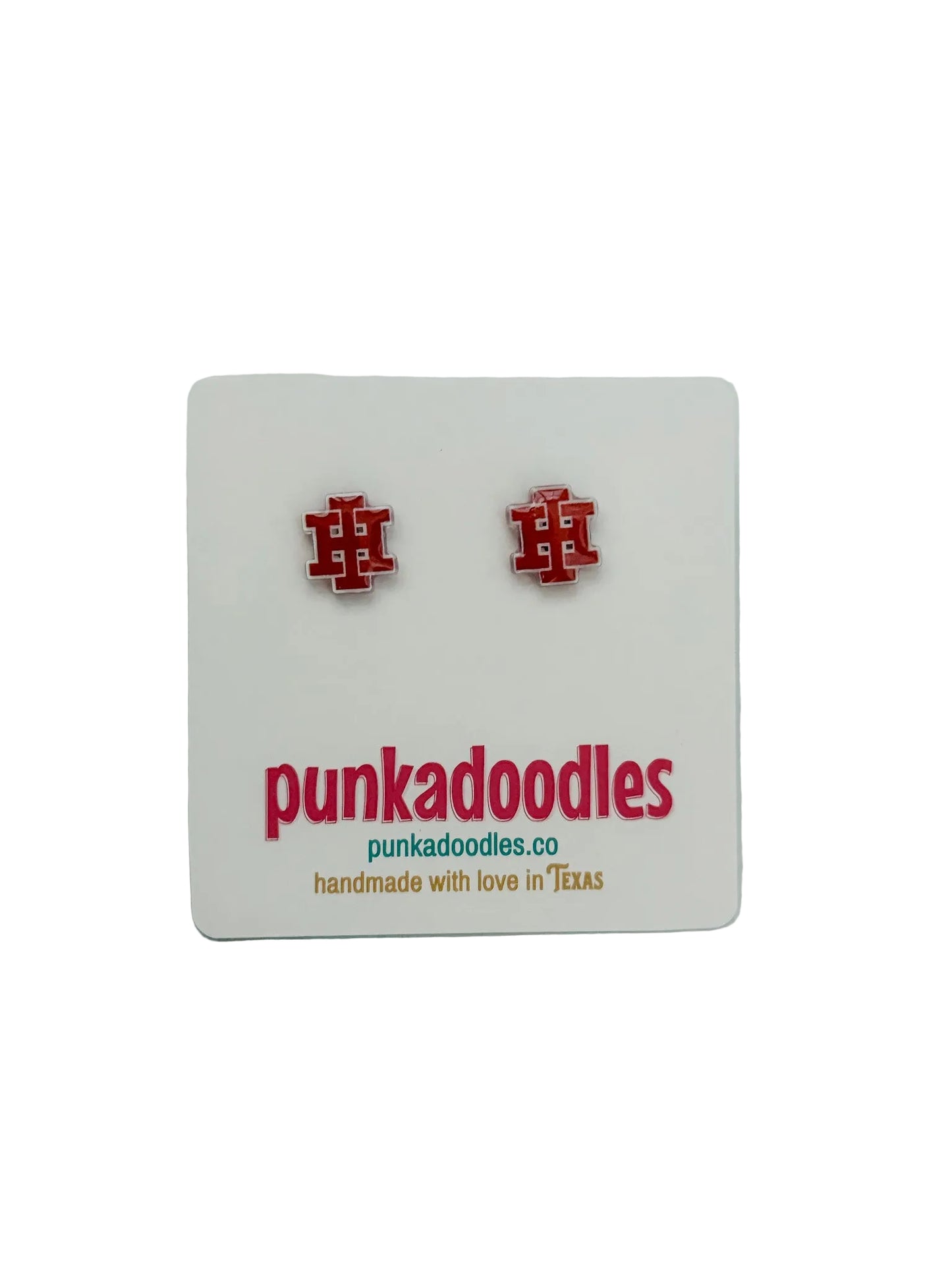 A pair of red and white enamel pin-back earrings displayed on a white card with the brand name 'punkadoodles' printed below, set against a light gray marble background.
